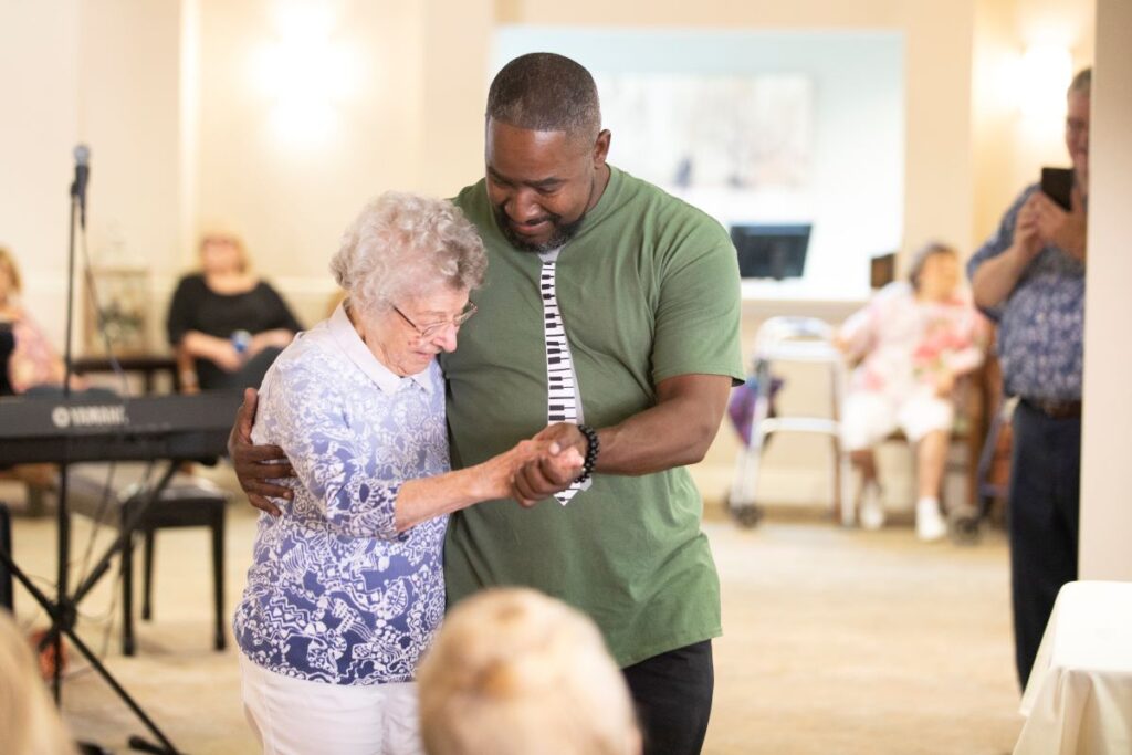 Senior woman resident dancing with community team member