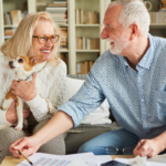 April 25 Events Page Image - The Residence at Whitehall Elderly man and woman smiling and holding small dog