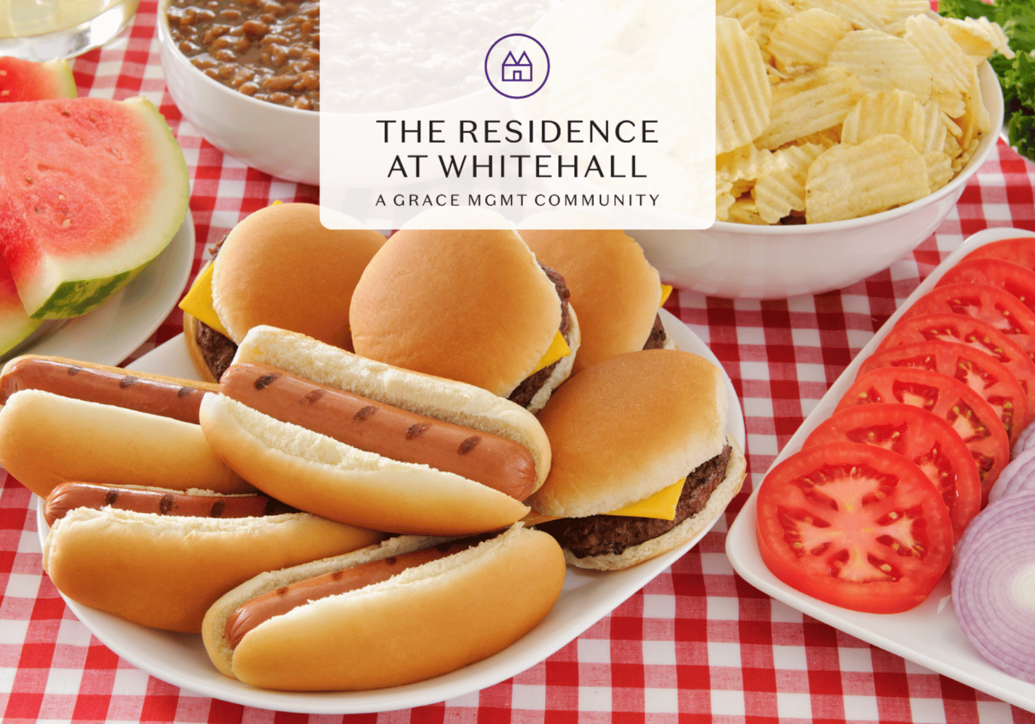 Brand banner for The Residence at Whitehall over a picnic table with hot dogs, burgers, watermelon and chips on a red-check tablecloth